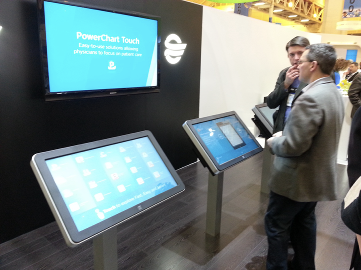 PowerChart Touch demonstrated on kiosk screens at a conference booth